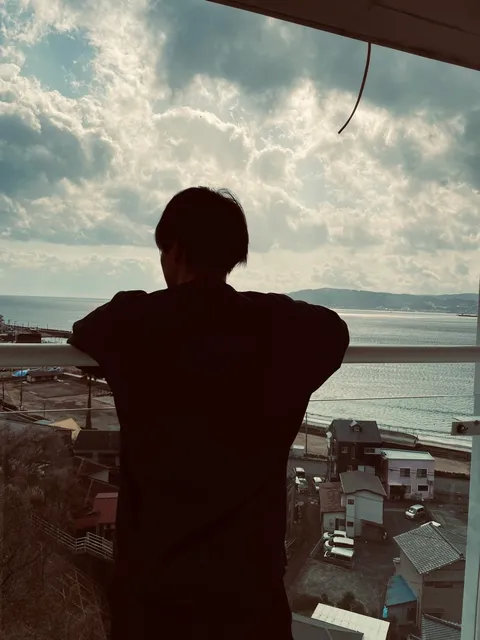 海を見つめ、前を向いて一歩を踏み出す人（Rise Journey のメインビジュアル）